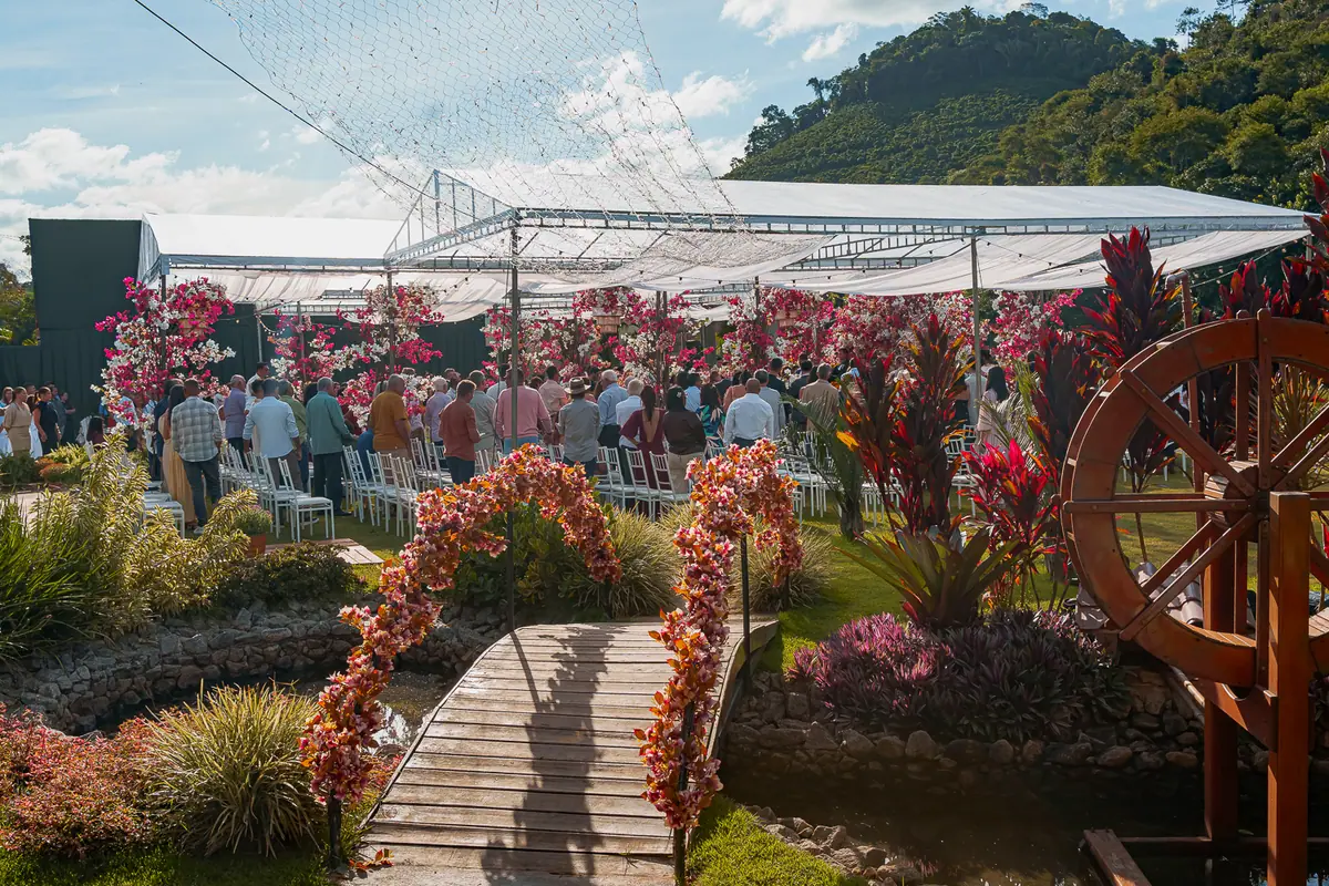 Ponte de madeira, roda d'água e jardim florido na área externa