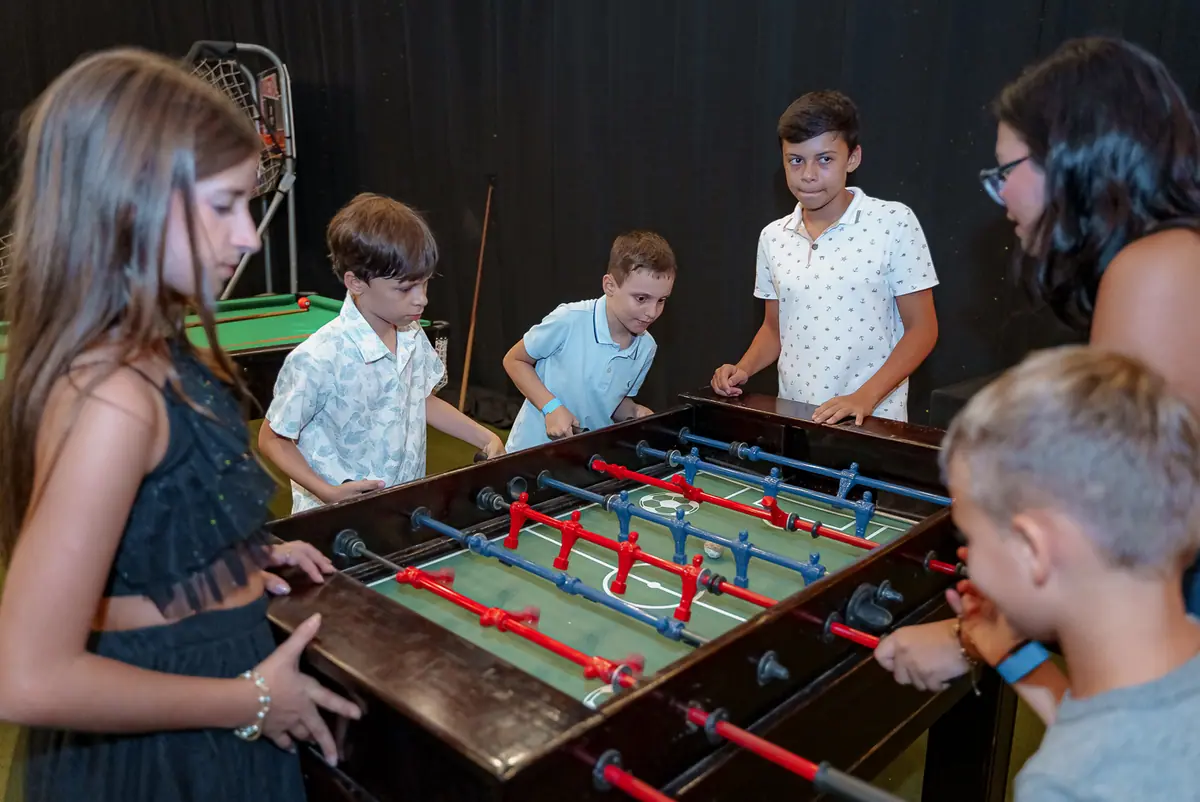 Crianças jogando pebolim no espaço de jogos