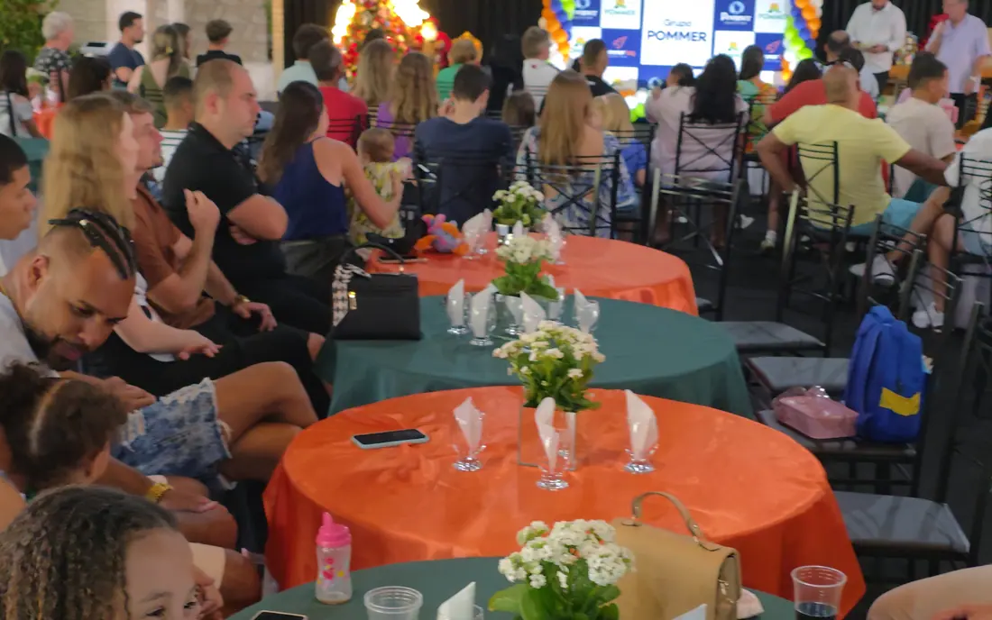 Convidados reunidos às mesas durante confraternização de empresa